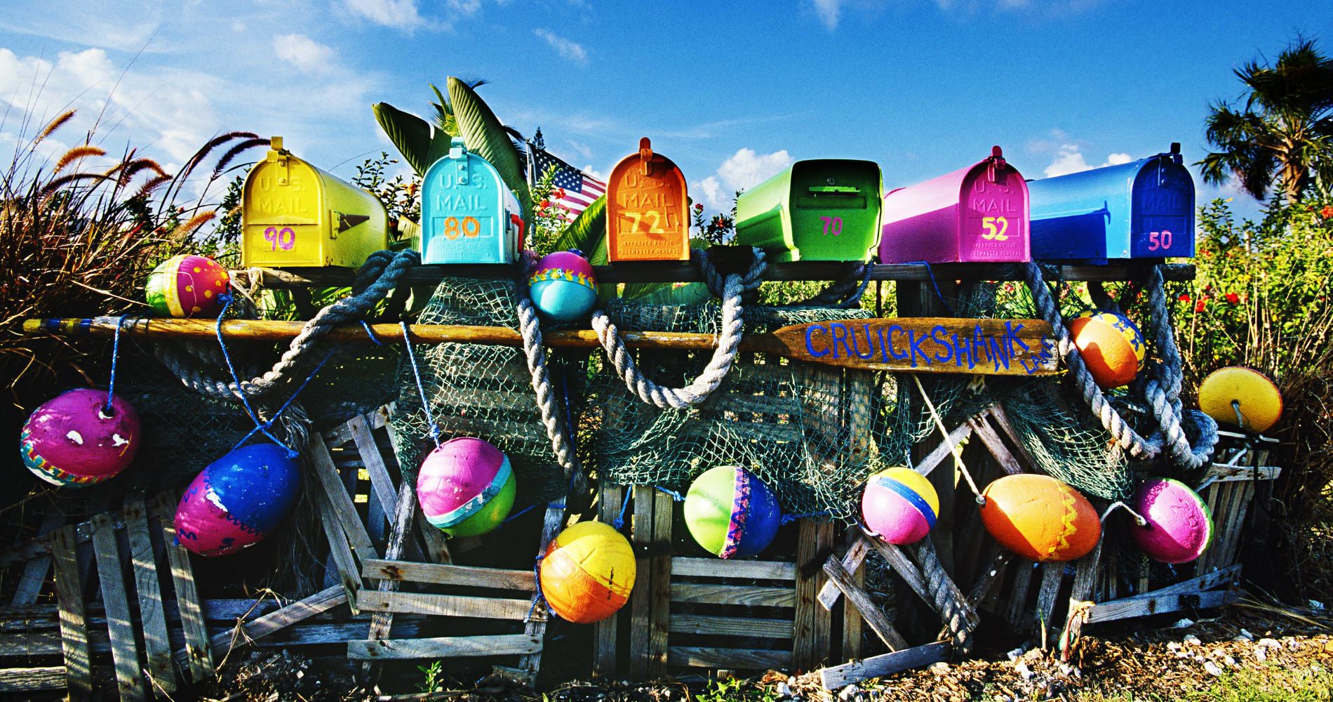 Multi-colored numbered mailboxes with netting and rope and colored balls with blue sky in background
