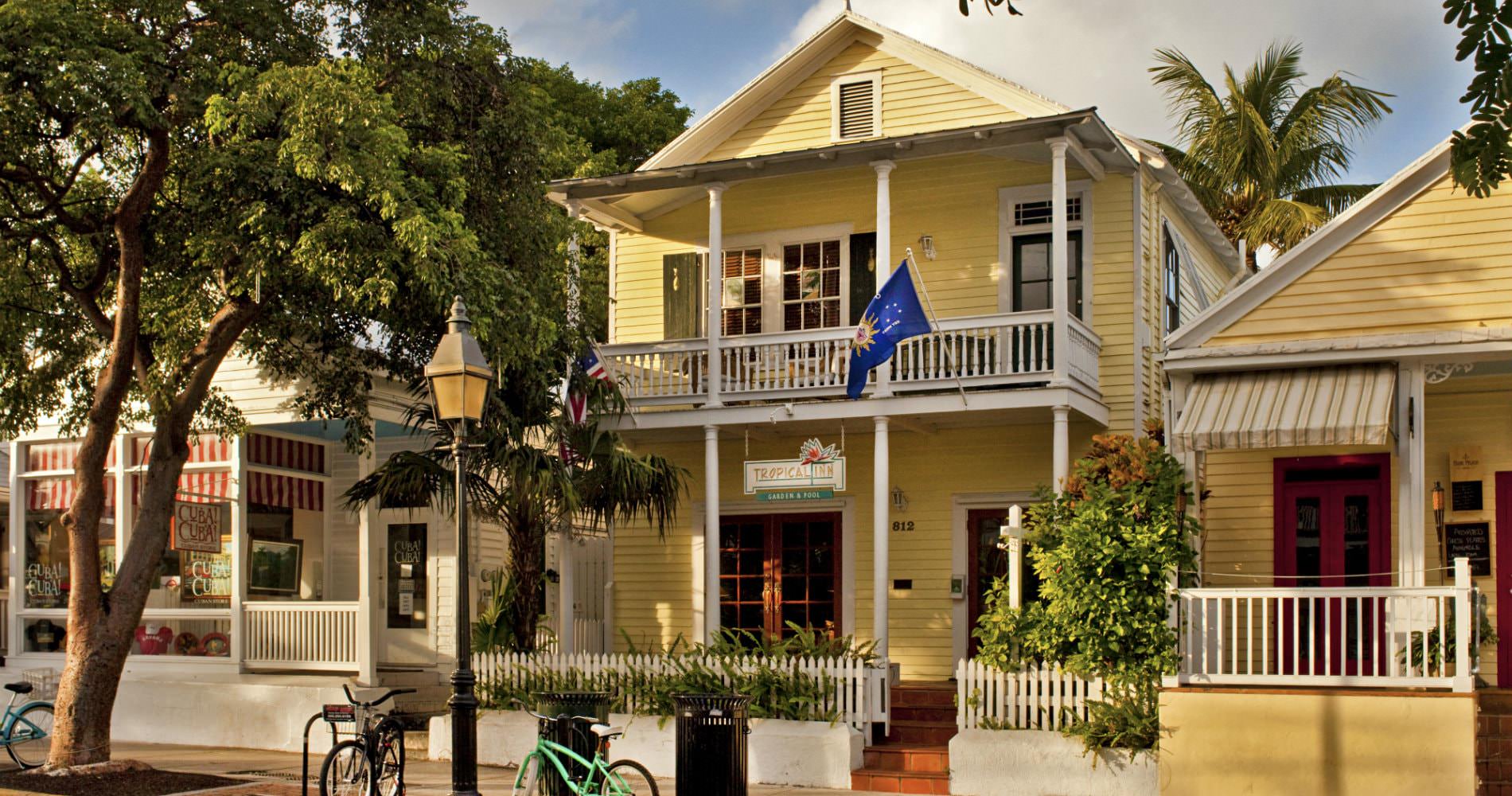 Bright yellow buildings with blue flag flying and green shutters and white picket railings