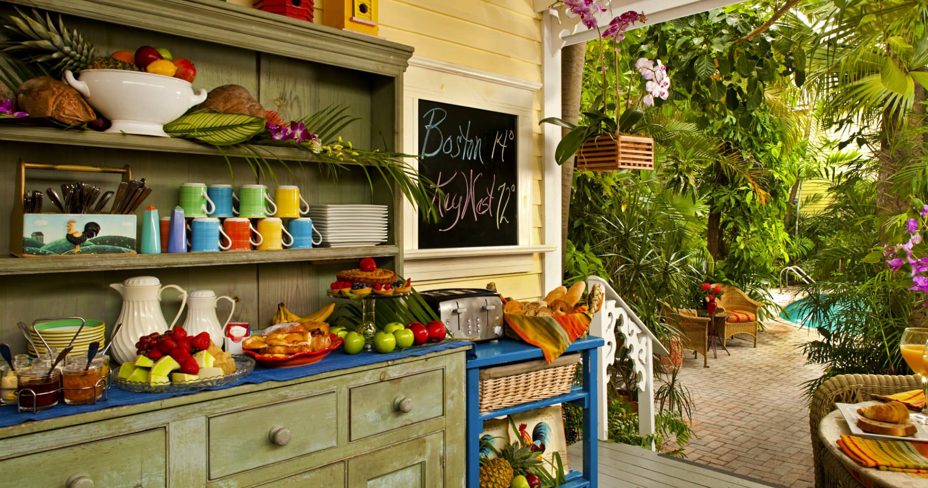 Buffet with variety of continental breakfast foods with a walkway going through trees leading to pool