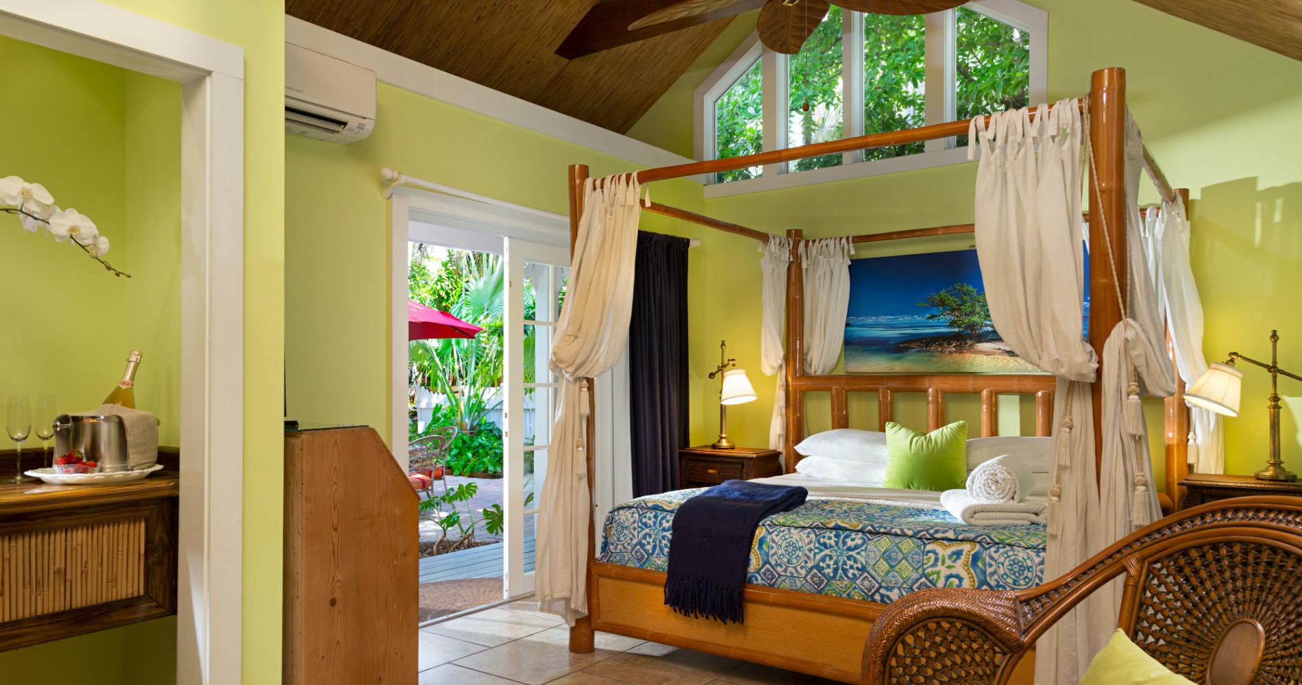 Bright yellow room with 4 poster canopy bed with connected bath and sliding glass door leading to patio