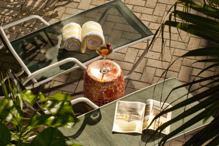 Mesh lounge chairs with yellow and white towels and magazine on chair with table containing champagne flute