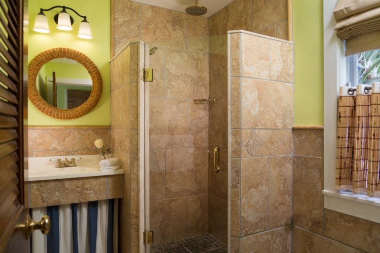 Yellow bathroom with glass tiled walk in shower with separate sink and mirror and window with bamboo curtains and blind