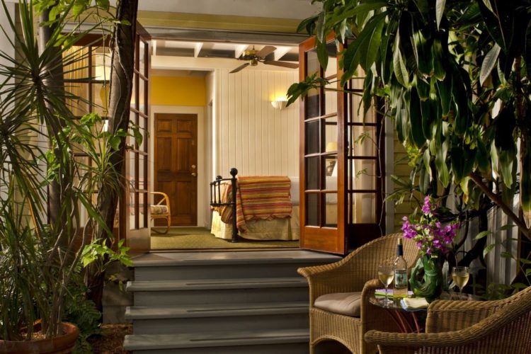 Entering yellow bedroom from patio with 3 steps leading into room with wicker chairs and round table on patio