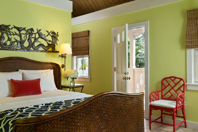 Bright yellow room with red metal cushioned chair and white open door leading to balcony