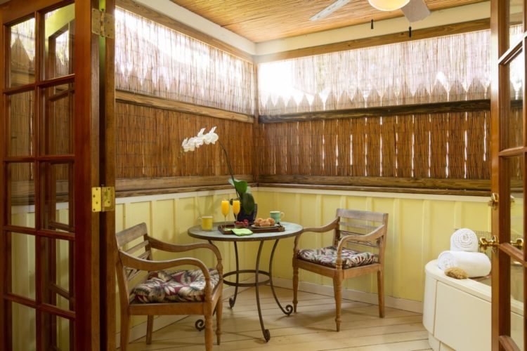 Sitting room with round table and wood cushioned chairs with bamboo curtains and hot tub