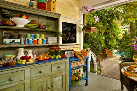 Buffet with variety of continental breakfast foods with a walkway going through trees leading to pool