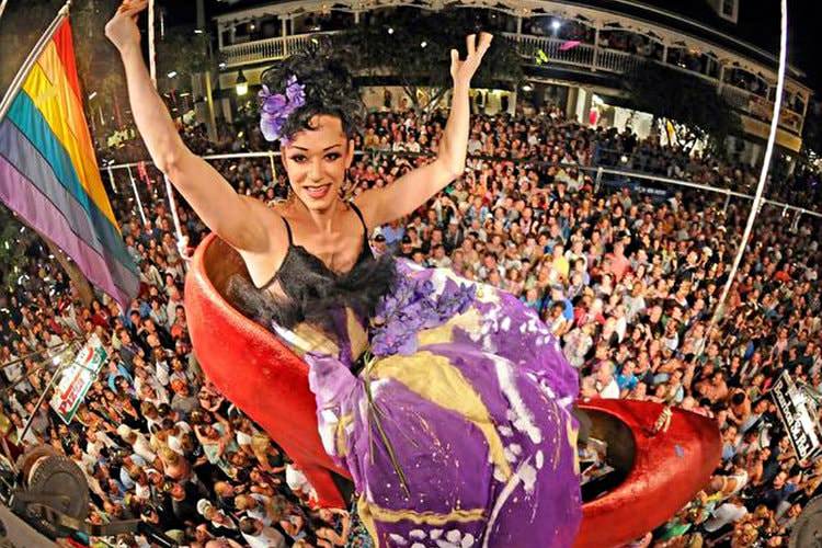 Woman in a giant red shoe suspended from the ceiling over a large crowd of people on new year’s eve