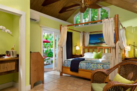 Bright yellow room with 4 poster canopy bed with connected bath and sliding glass door leading to patio