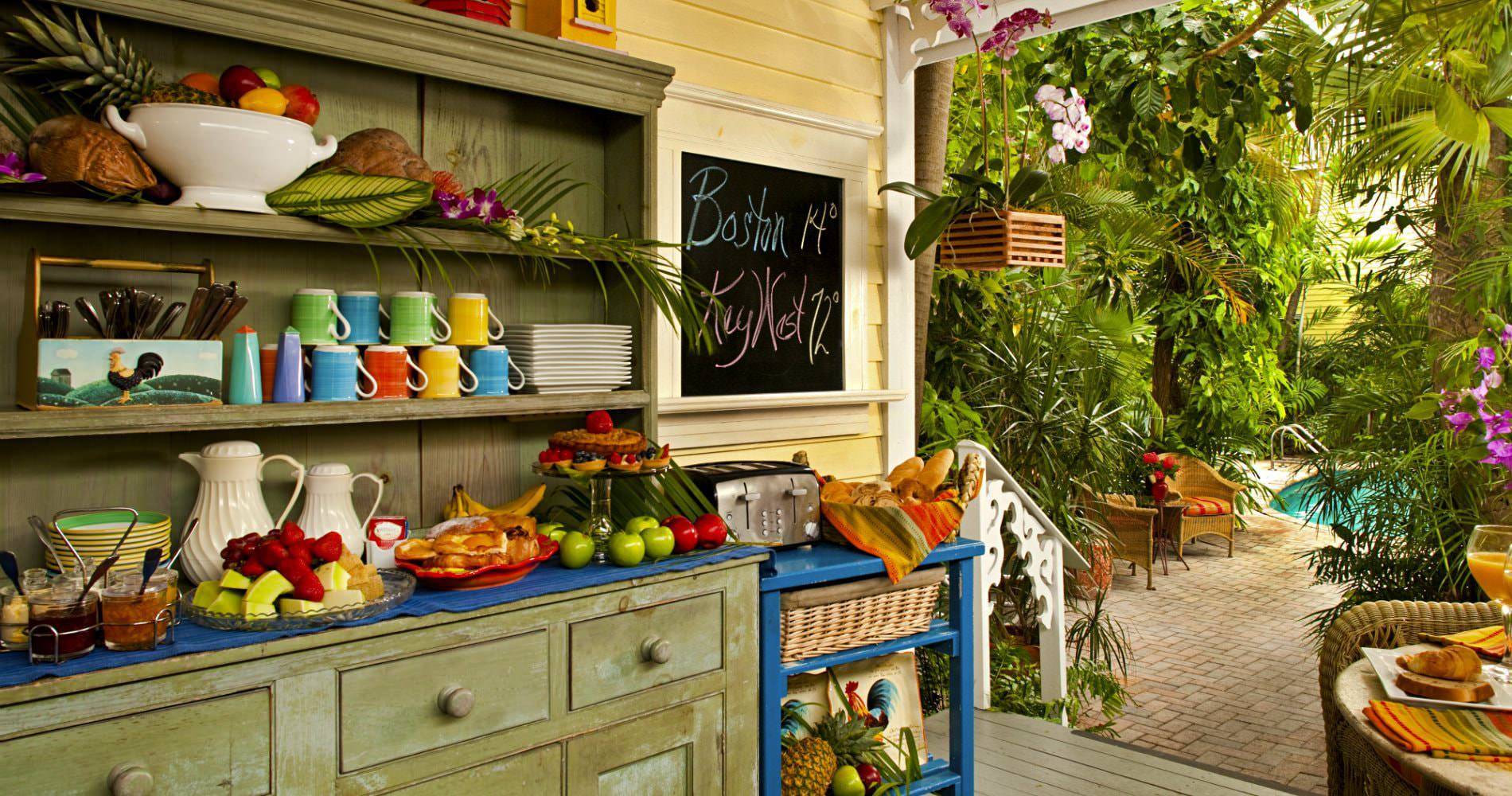 Buffet with variety of continental breakfast foods with a walkway going through trees leading to pool